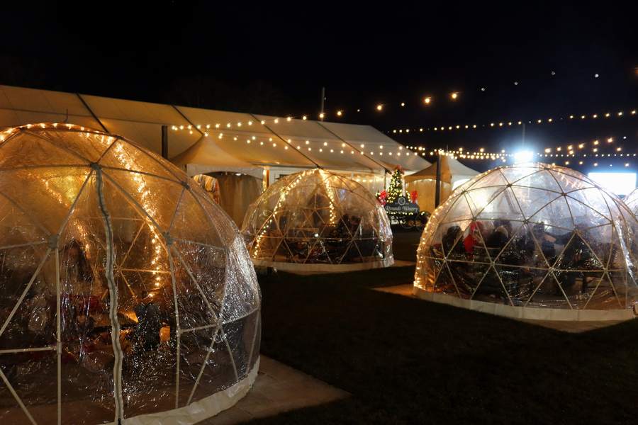Illuminated geodesic igloos with string lights and a Christmas tree at Vintner Wonderland