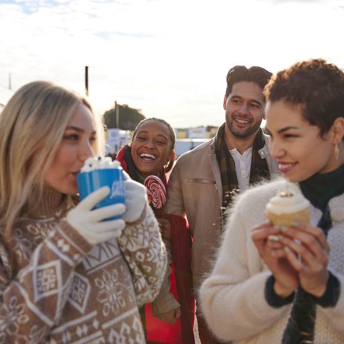 Guests in winter coats sharing hot cocoa and holiday desserts at an outdoor winery celebration