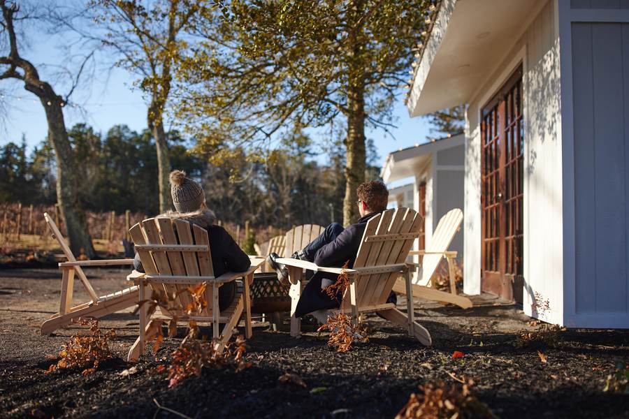 Guests relaxing in Adirondack chairs beside the vineyard on a winter afternoon