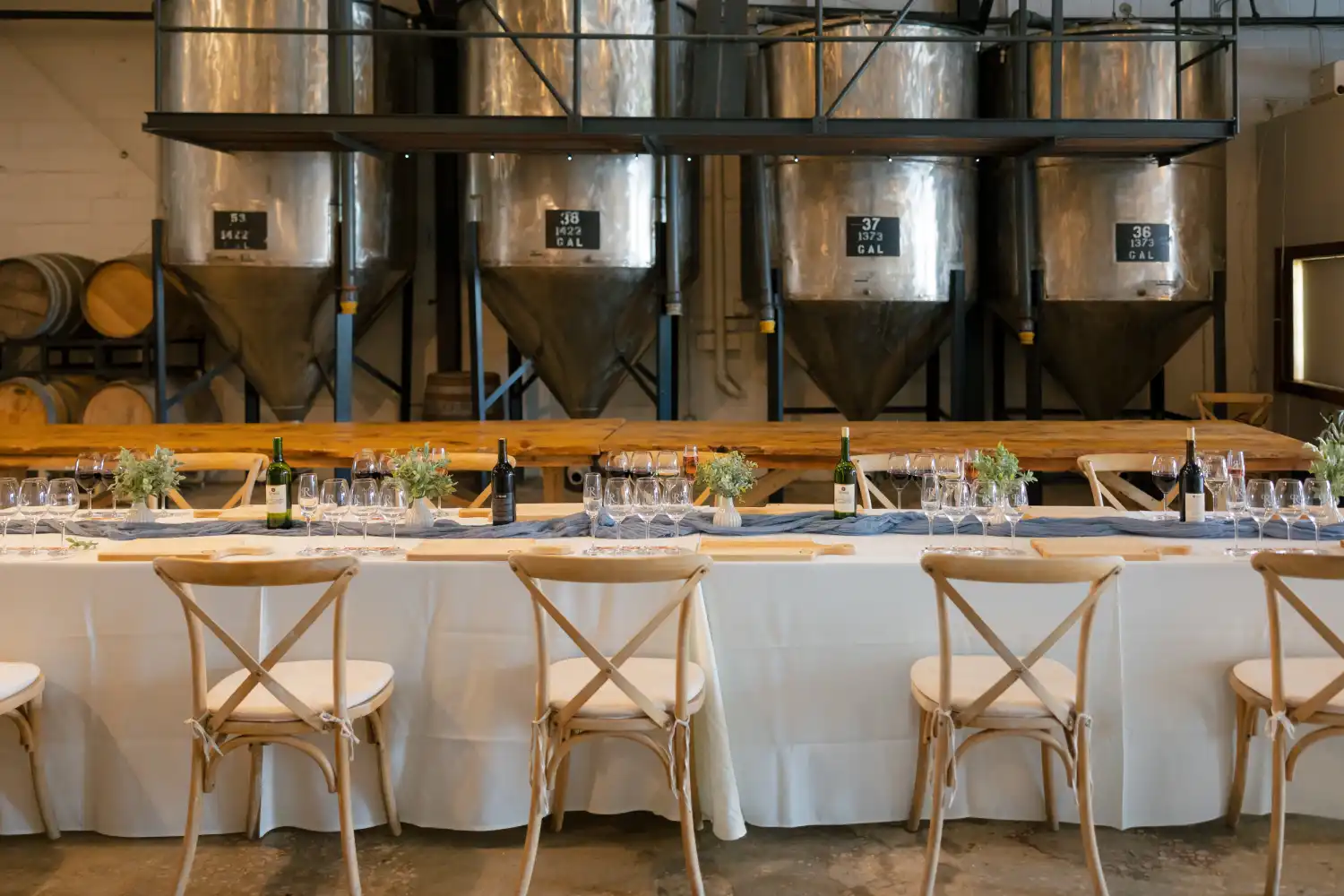 Long banquet table set with estate wines for a private holiday dinner in the winery production room